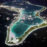 Aerial view of the Chagos Islands with clear blue waters, lush green atolls, and strategic military significance, symbolizing British sovereignty issues.