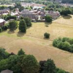 Aerial view of Corbett Meadow in Amblecote, Stourbridge, showing open green space, trees, and nearby housing development, highlighting the area's ecological importance and conservation efforts.