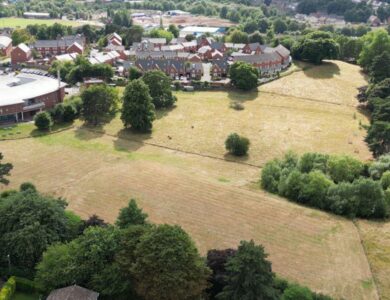Aerial view of Corbett Meadow in Amblecote, Stourbridge, showing open green space, trees, and nearby housing development, highlighting the area's ecological importance and conservation efforts.